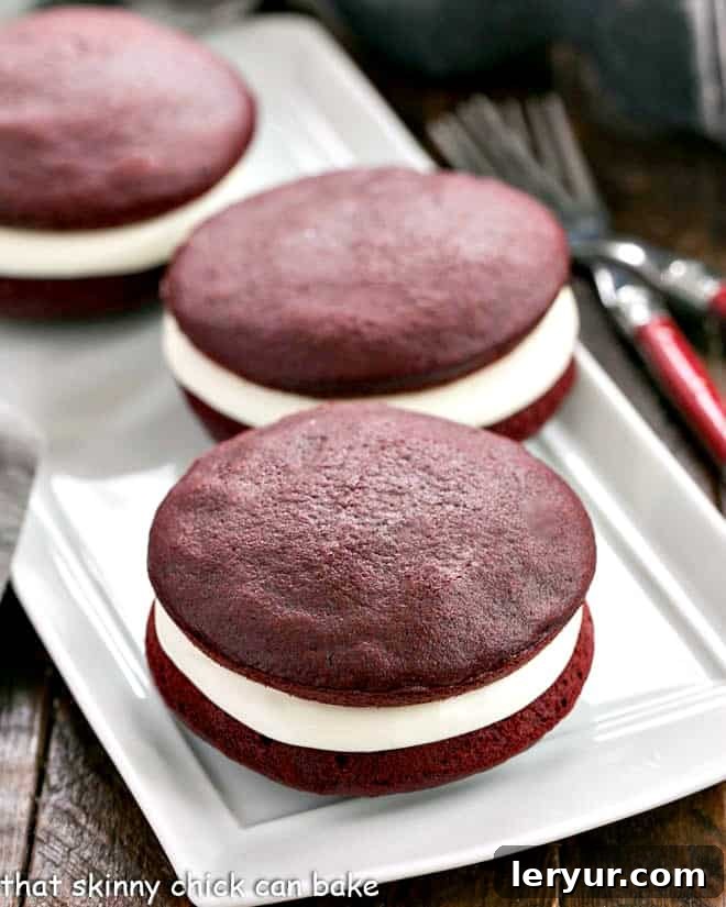 Red Velvet Whoopie Pies: A delightful twist on the classic, featuring tender red velvet cake rounds and a luscious cream cheese filling. Red velvet whoopie pies on a white serving tray, showcasing their vibrant color and creamy filling.