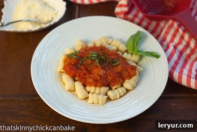 Pillowy Ricotta Gnocchi in Tangy Marinara 3 Ricotta Gnocchi with Marinara on a white plate with a basil garnish, showcasing a beautifully plated, enticing dish.